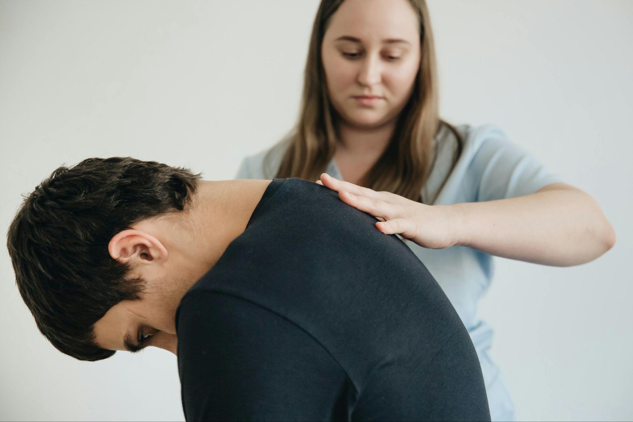 Chiropractor examining a patient’s upper back posture.